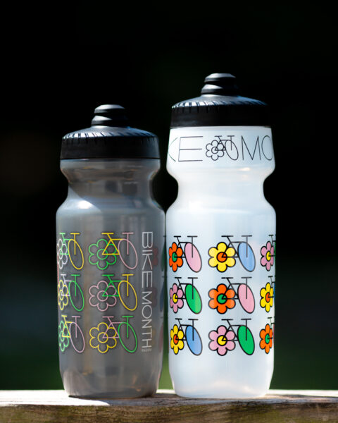 two colorful water bottles, one short and dark grey, one tall and clear