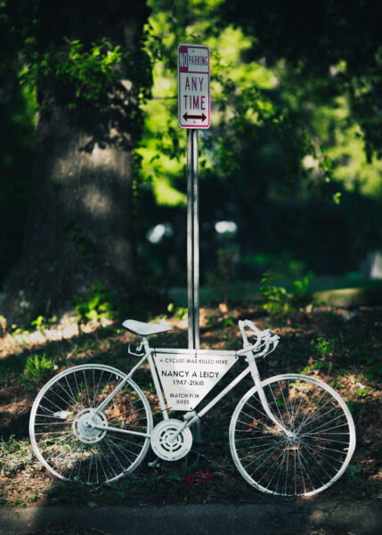 A ghost bike locked to a street sign