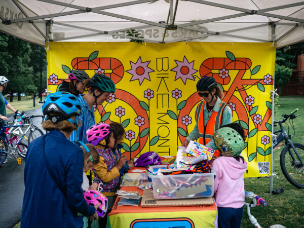 Group of kids and parent decorating their bike helmets at a table